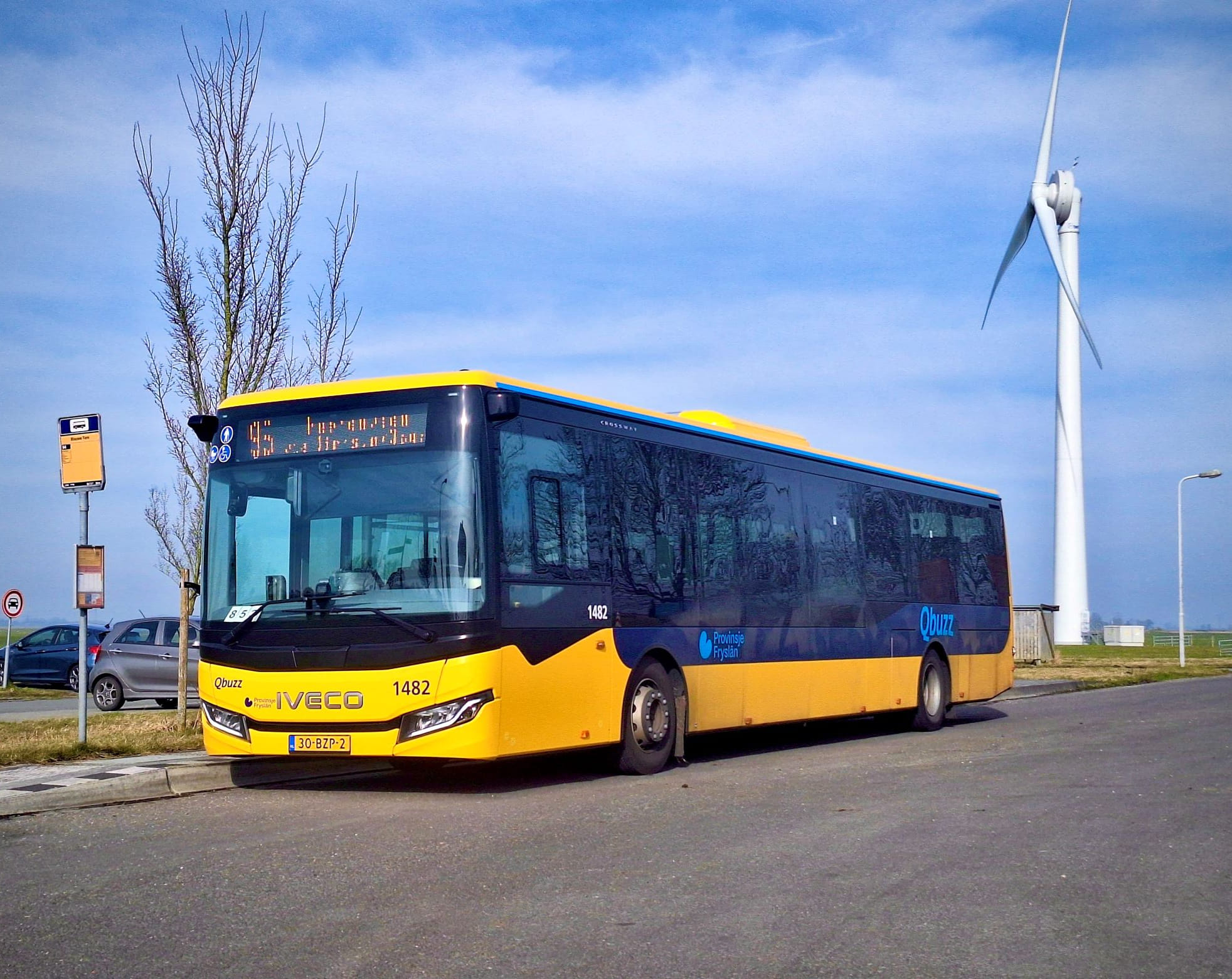 Lijn 95 staat stil bij een halte met een windmolen op de achtergrond