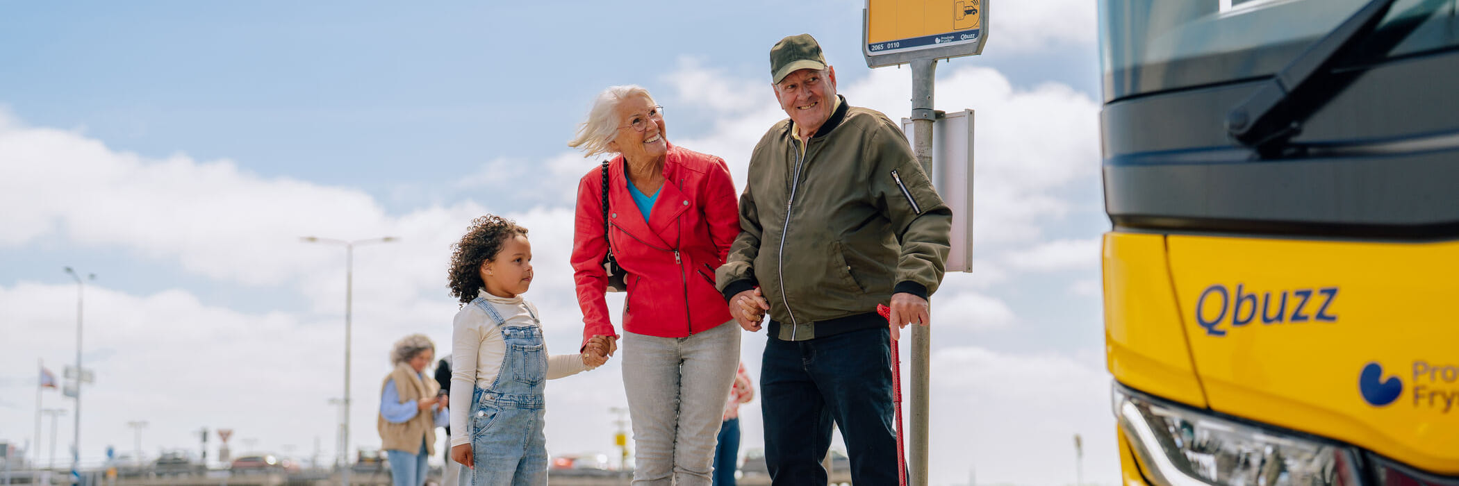 Opa en oma staan met kleinkind bij bushalte