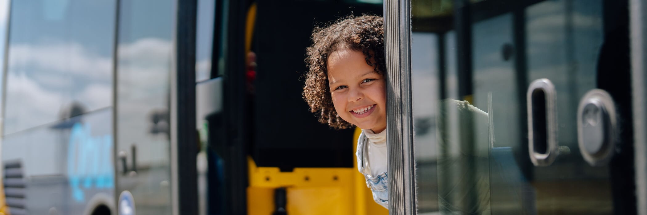 Klein kind kijkt glimlachend bij de deuropening naar buiten